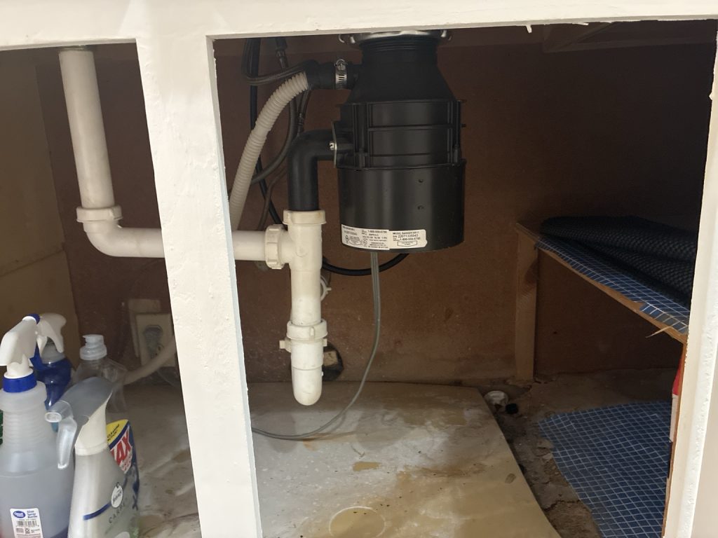 Garbage disposal and kitchen drain piping from a real service call involving eggshells and a dishwasher backup.